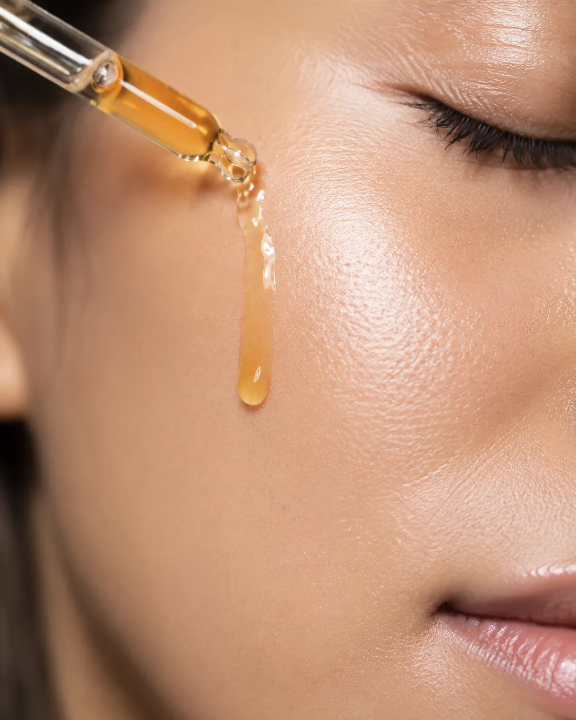 Golden serum drop on luminous cheek skin